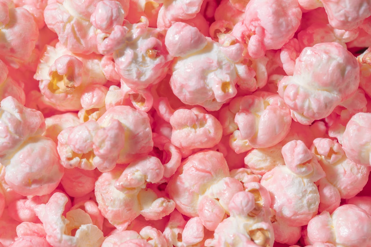 Vibrant close-up of pink candy coated popcorn, perfect for sweet snack themes.